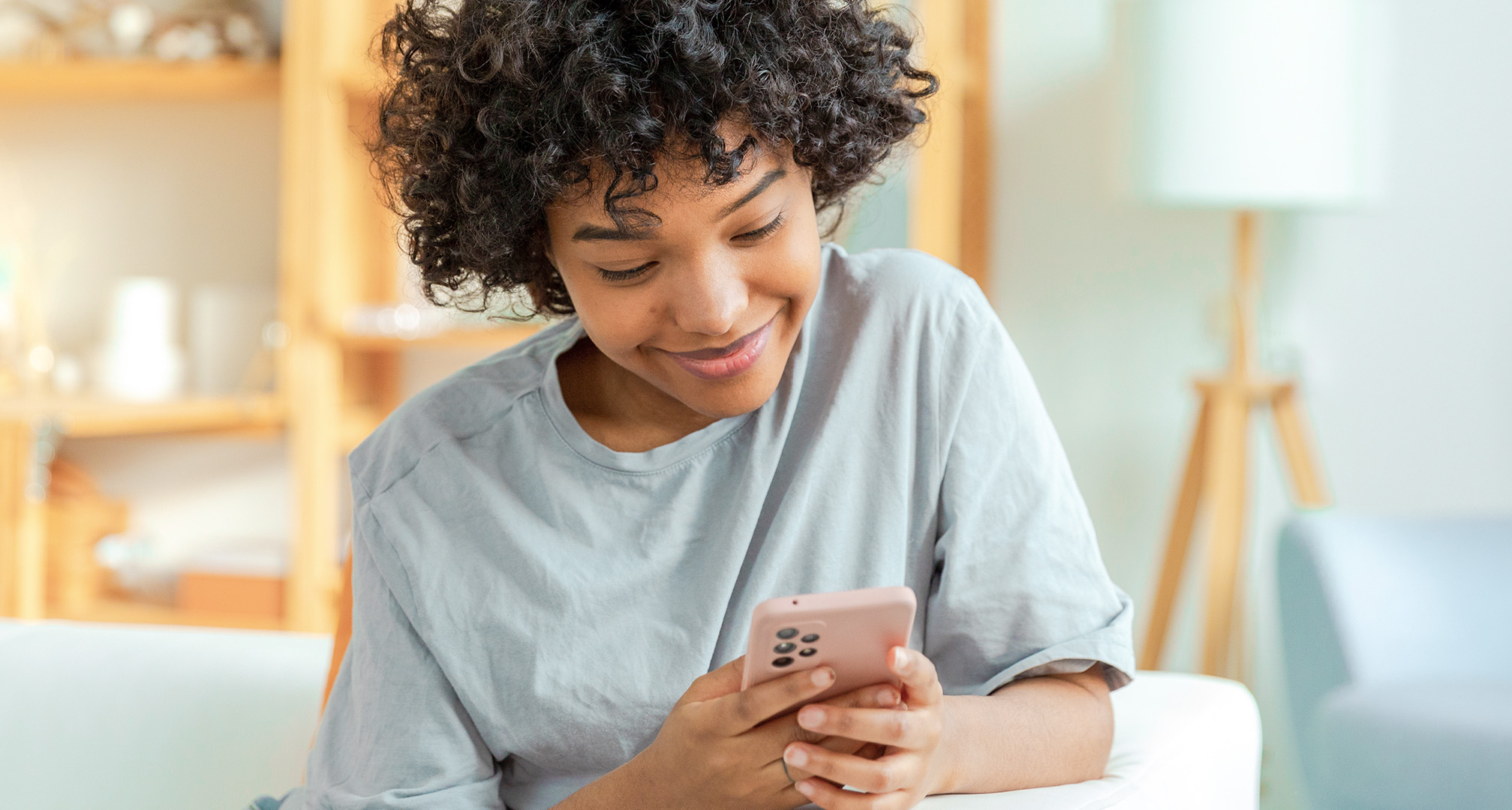 stambiu planu besišypsantis žmogus, žiūrintis į savo telefoną