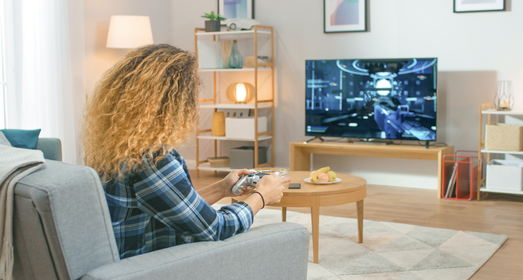 žmogus ilgais garbanotais plaukais svetainėje žaidžia vaizdo žaidimus per televizorių